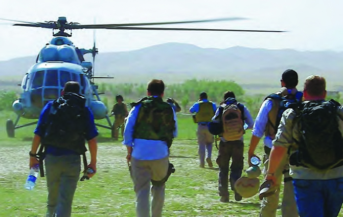 Image of several people with backpacks walking towards a helicopter.